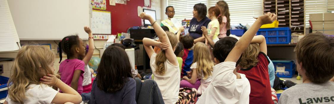 A diverse group of children receiving guidance and support in an inclusive classroom environment, with a teacher providing individualized attention