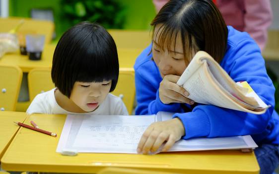 A parent or teacher sitting with a child, reviewing a printed or digital test report together in a supportive, encouraging manner